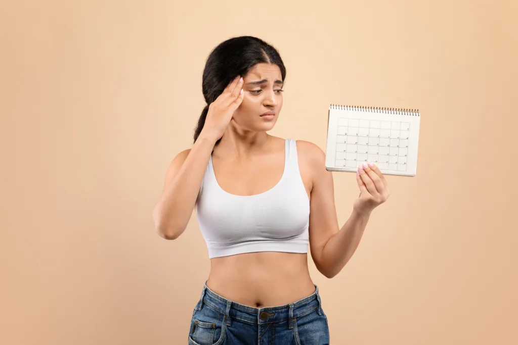 concerned young indian woman holding blank menstrual cycle calendar (1)
